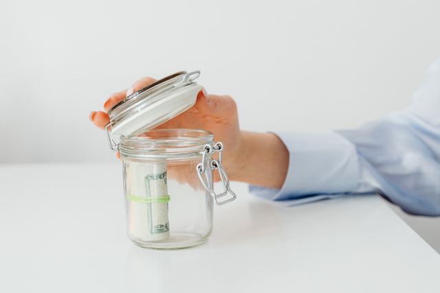 a person opening a jar with savings inside